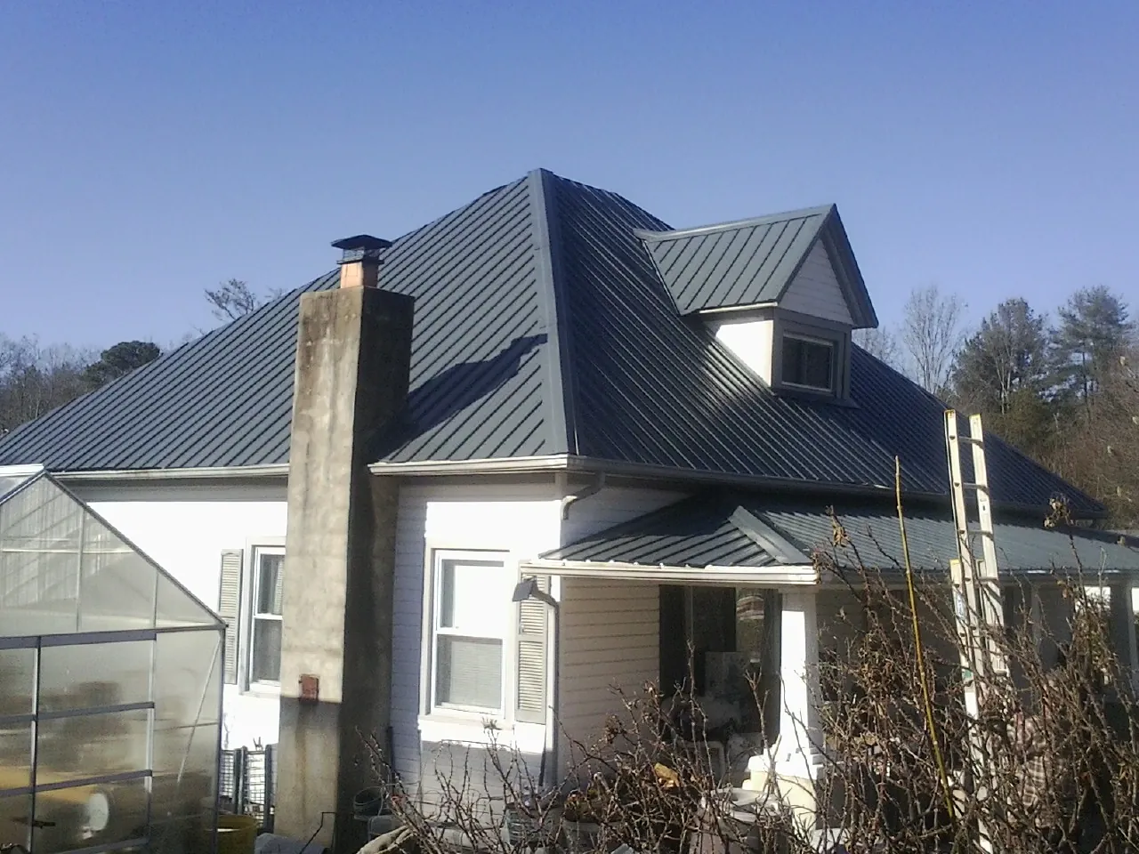 Dark blue standing seam metal roof on a white farmhouse with dormer — Slate & Tile Roof Repair by Roofing Brothers in Centertown