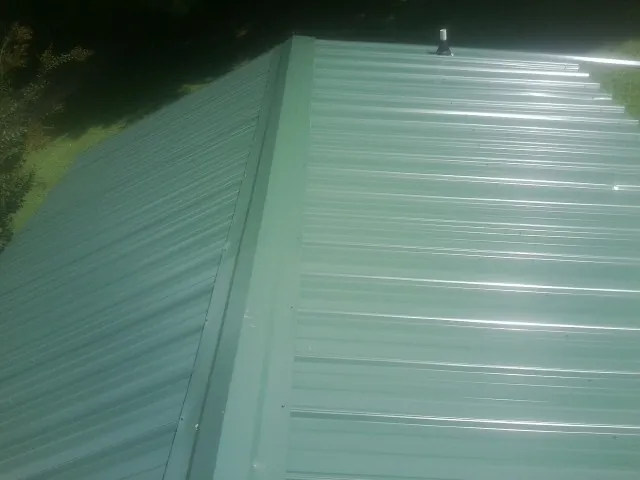 New green metal panels meeting at the ridge of a roof — Flat Roof Repair work by our crew in Centertown
