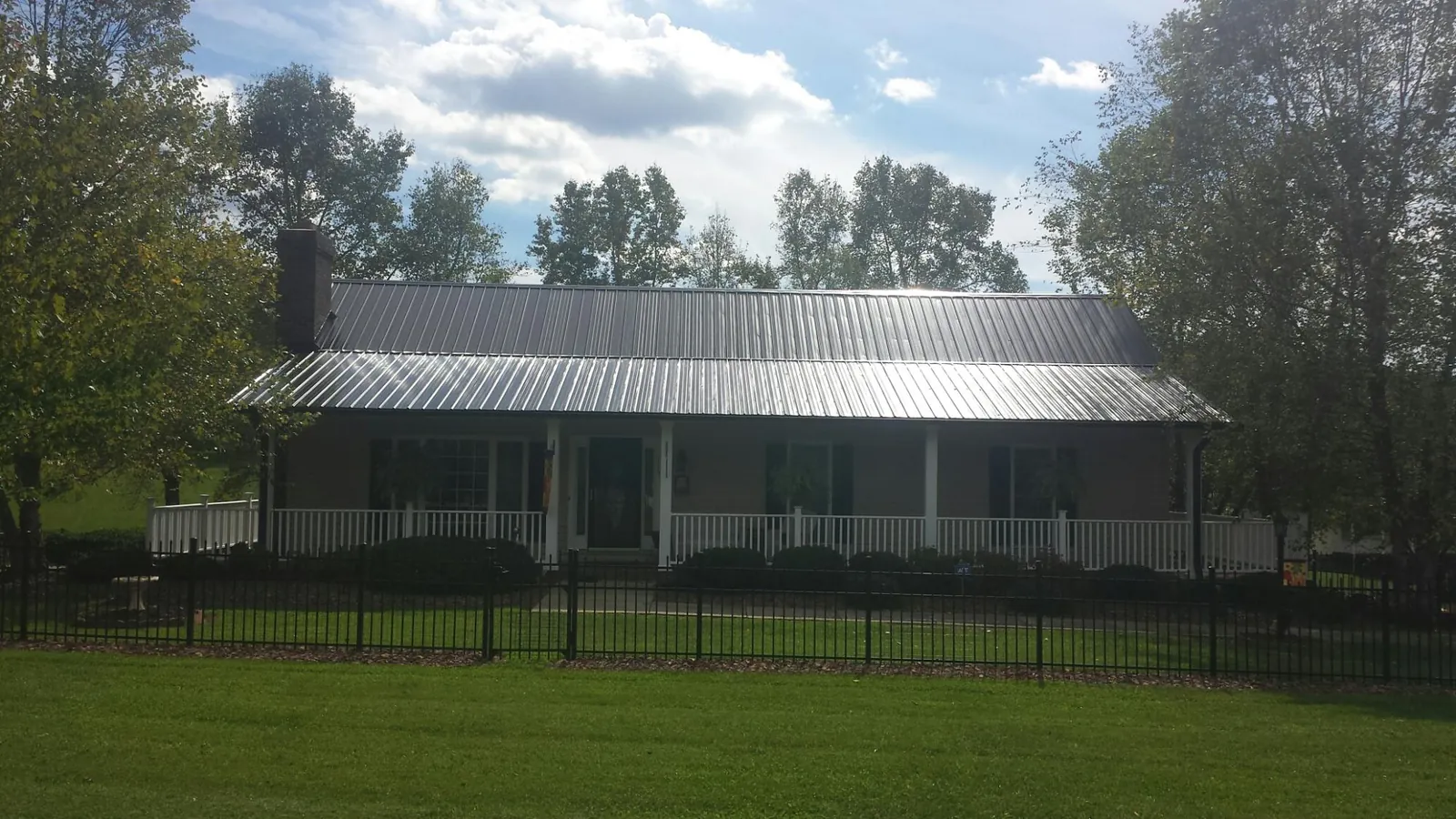 Gray metal roof on a brick ranch with a full width front porch — Gutter Guard Installation work by our crew in Centertown