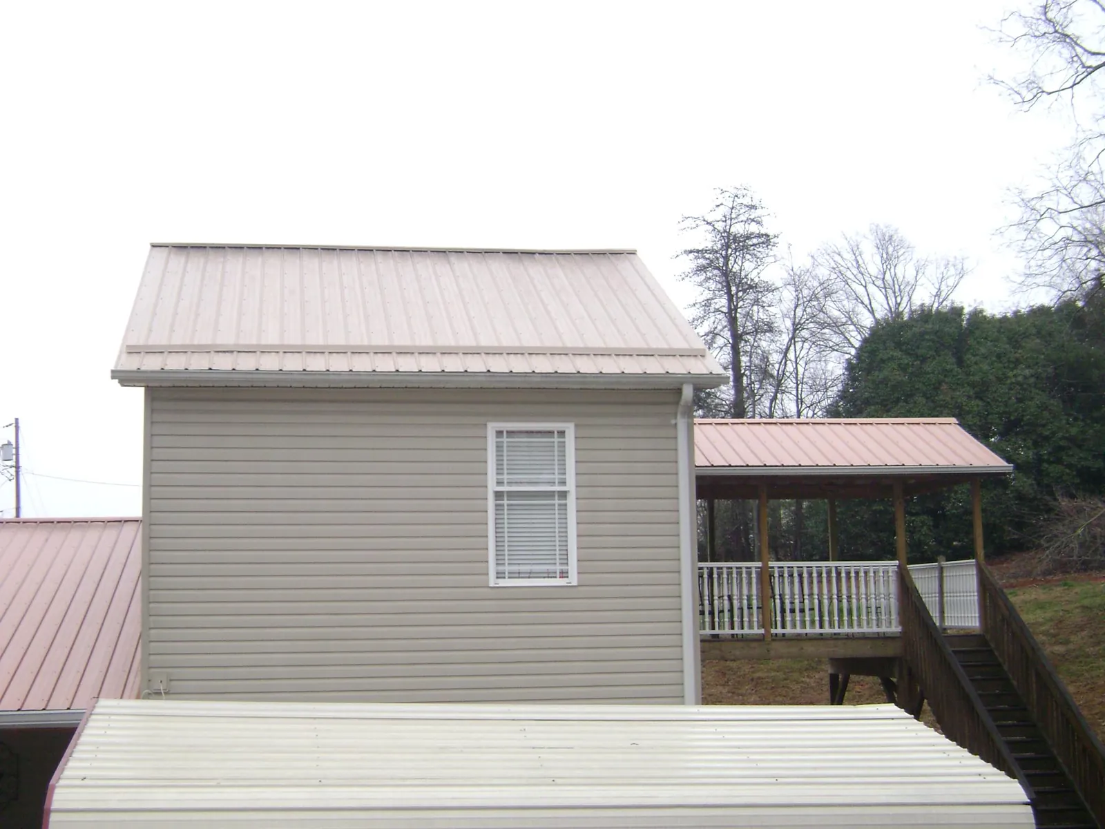Tan metal roofs on a two story addition and attached porch, from a Roof Replacement job in Centertown