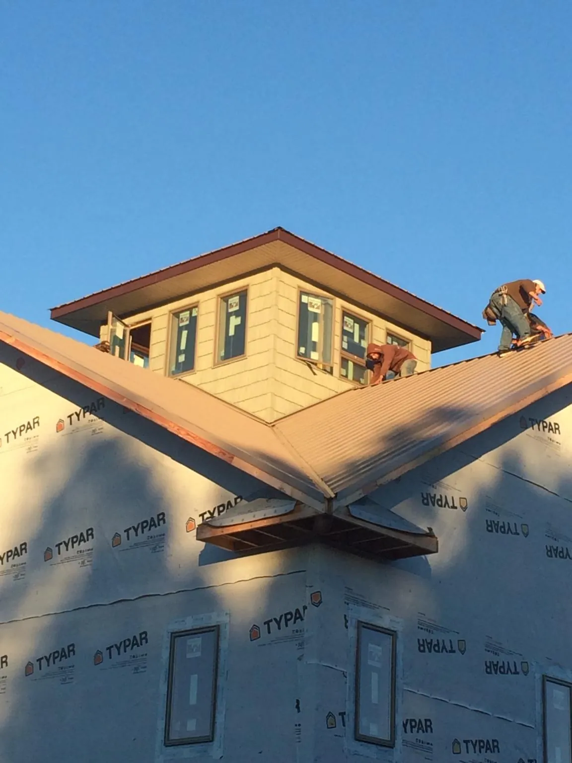 Roofers working around a rooftop cupola on a new metal roof at sunset — Roof Waterproofing in Centertown by Roofing Brothers